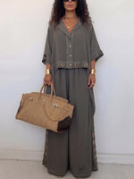 Conjunto de dos piezas para mujer: camisa holgada abotonada y pantalón de pierna ancha. Un atuendo informal y relajado con detalles de ojales metálicos.