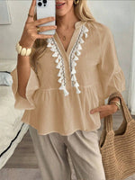 Top de mujer con cuello en V, botones y borlas.